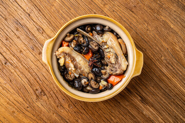 Lamb chops stewed with delicious mushrooms in a clay pot on a wooden table