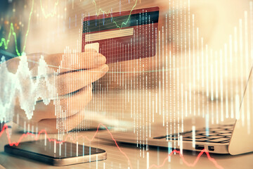 Multi exposure of woman on-line shopping holding a credit card and financial graph drawing. Stock market E-commerce concept.