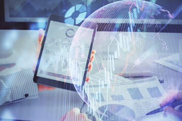 Double exposure of man's hands holding and using a digital device and forex graph drawing. Financial market concept.