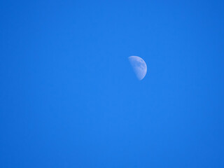 View of the moon on a clear winter day. Blue sky. Partial Moon visible
