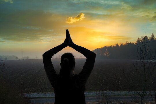 Sillouethe eine jungen Frau beim Yoga w&auml;hren eines Sonnenaufgangs