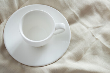 White cup on a small plate / saucer on a light background close up