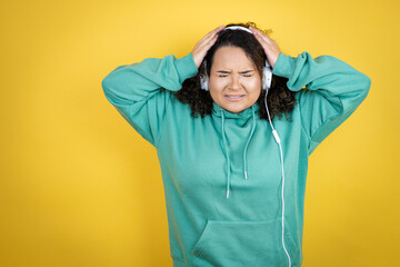 Fototapeta na wymiar Young african american girl wearing gym clothes and using headphones suffering from headache desperate and stressed because pain and migraine with her hands on head