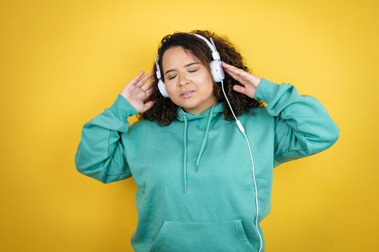 Young african american girl wearing gym clothes and using headphones dancing and listening to music with a happy face standing and smiling with a confident smile showing teeth