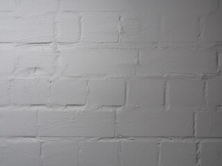White brick background partially casually painted over with paint or plaster. Textured surface of a modern industrial room finish. Cheap and simple painted brickwork.