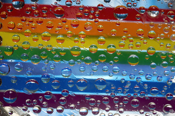 Rainbow. Multicolored drops of water are located against a blue background with strips of rainbow...