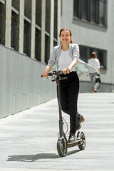 Young woman riding electric scooter in urban background © Oleksandr Kozak