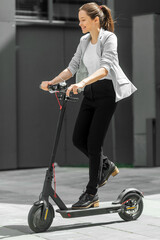 Young woman riding electric scooter in urban background