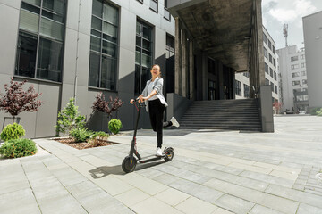 Young woman riding electric scooter in urban background