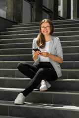 Fototapeta na wymiar Young woman sitting on stairs with smartphone