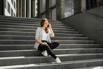 Young woman sitting on stairs talking on smartphone