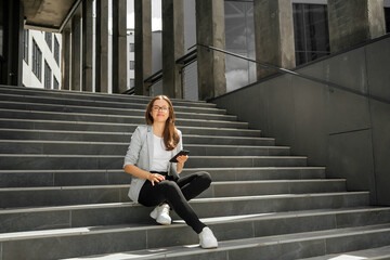 Young woman sitting on stairs with smartphone