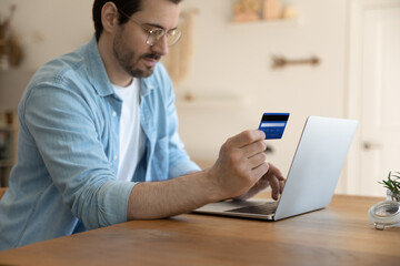 Close up of millennial Caucasian man use laptop shopping paying online with credit card. Young male buyer or client make payment on internet on computer with secure banking service system.