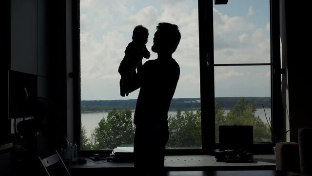 Silhouette Middle Portrait of Young Father while He Raises Up his Little child Above the Head. Communication and Connection Tiny Daughter and Father, Togetherness, Cozy Interior.