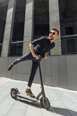 Fototapeta na wymiar Young man riding electric scooter in urban background