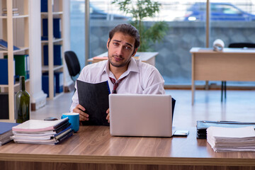 Young male alcohol addicted employee working in the office
