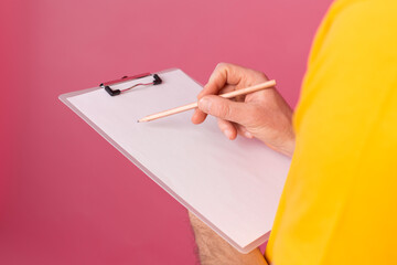 Young bearded employee man casual wear taking notes against a pink background