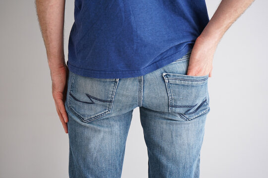 Legs of a young man in jeans on a gray background.