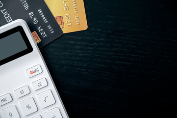 Obraz premium Credit cards and calculator on black wooden table, top view and copy space.