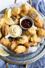 Closeup view of a circular tray full of japanese fish tempura over a metallic cooling rack.