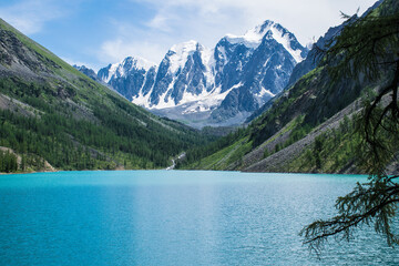 Fototapeta na wymiar The pearl of the Altai Mountains, Lake Shavlo, with three glacier-covered peaks towering above it, is a Fairy tale, a Dream and a Beauty that is reflected in the lake water.