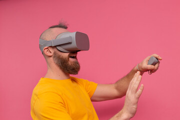 Handsome positive bearded man playing game in vr glasses studio background