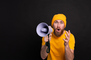 Attention! European man shouting in megaphone on black background