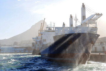 Fototapeta premium Cargo ships docked in Cape Town harbour, Lions Head mountain in the background