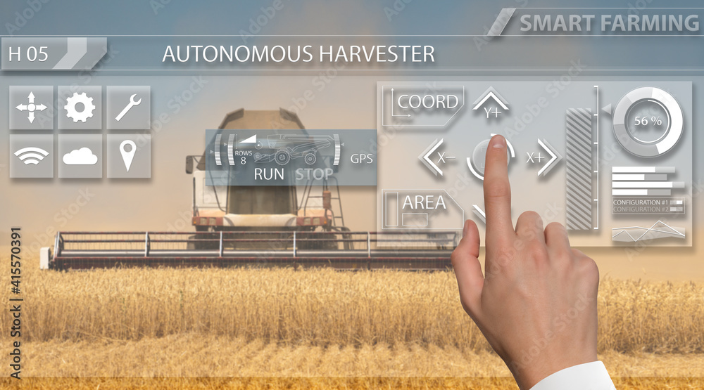 Fototapete Remote control of an autonomous combine in the field.  Hand touching screen.
