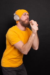 Handsome man in casual dancing with headphones isolated on black background