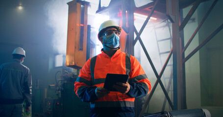 Obraz na płótnie Canvas Male supervisor in mask using tablet near worker
