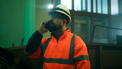 Factory worker answering phone call in workshop