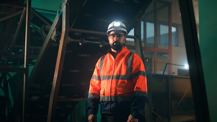 Male engineer looking at camera near machinery