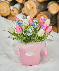 bouquet of spring flowers on a background of woodpile with large logs