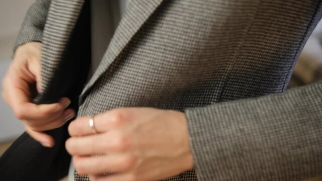 A young woman puts on a jacket, fastens a button close-up. White shirt. Businessman. Getting ready, getting dressed for work. Business style. Classic clothing