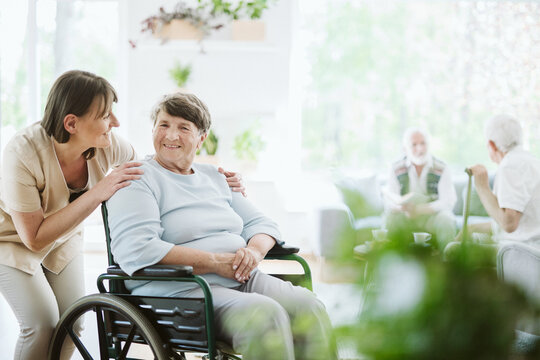 Happy caregiver with elder patient on the wheelchair
