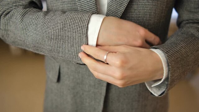 The girl adjusts the sleeves of her shirt and jacket. Close-up of classic clothing. A businessman is going to get dressed for work