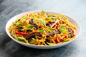 Stir fry noodles with beef and vegetable in white bowl. asian style food