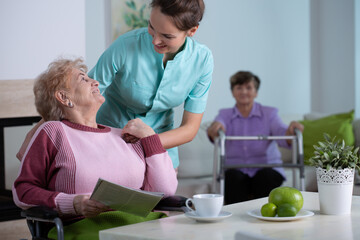 Female senior residents in living room of nursing facility with supporting nurse