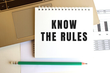 Notepad with the text KNOW THE RULES is on the laptop keyboard. Business concept.