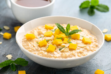 Rice pudding with cinnamon and mango in white bowl