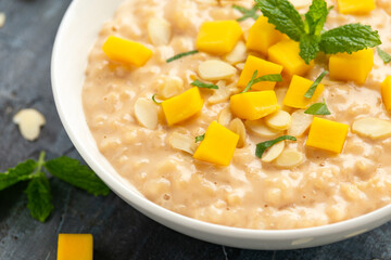 Rice pudding with cinnamon and mango in white bowl