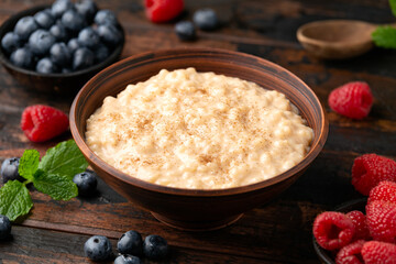 Rice pudding with cinnamon and blueberry, raspberry in rustic bowl