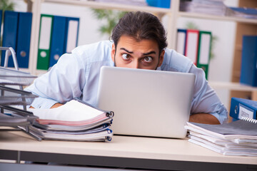 Young male employee unhappy with excessive work in the office