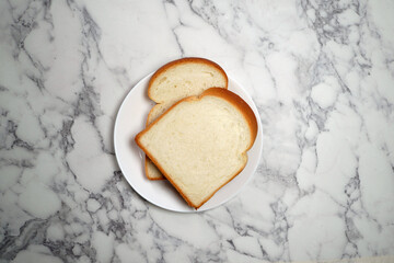 Two slices of bread on white plate on marble background