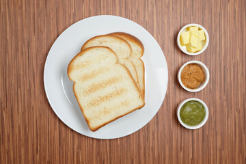 Toasted bread with butter, kaya, jam, peanut butter on wooden verneer table