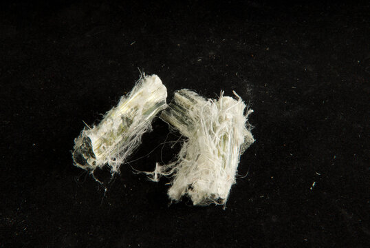 Closeup of naturally-occurring fibrous silicate mineral asbestos on dark background