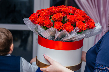 A bouquet of roses in a box as a gift. The girl is holding a box with roses to give for her...