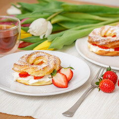 Profiteroles or cream puff cakes with whipped cream and strawberries