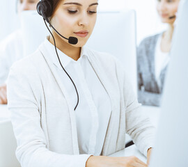 Call center. Group of diverse operators at work. Beautiful woman in headset communicating with customers of telemarketing service. Business concept